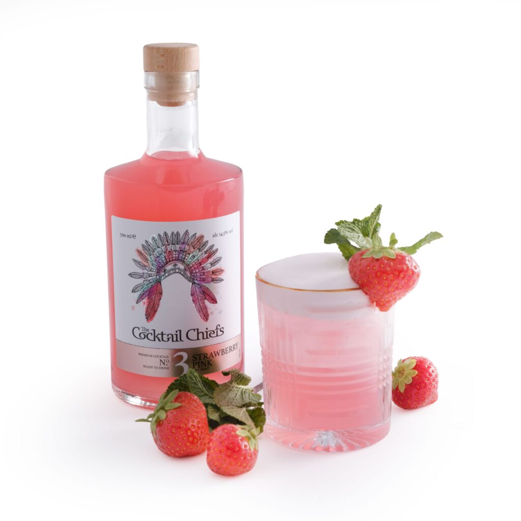 Nahaufnahme des Strawberry Pink Cocktails mit leuchtend roter Farbe, garniert mit frischen Erdbeeren und einem Minzzweig.