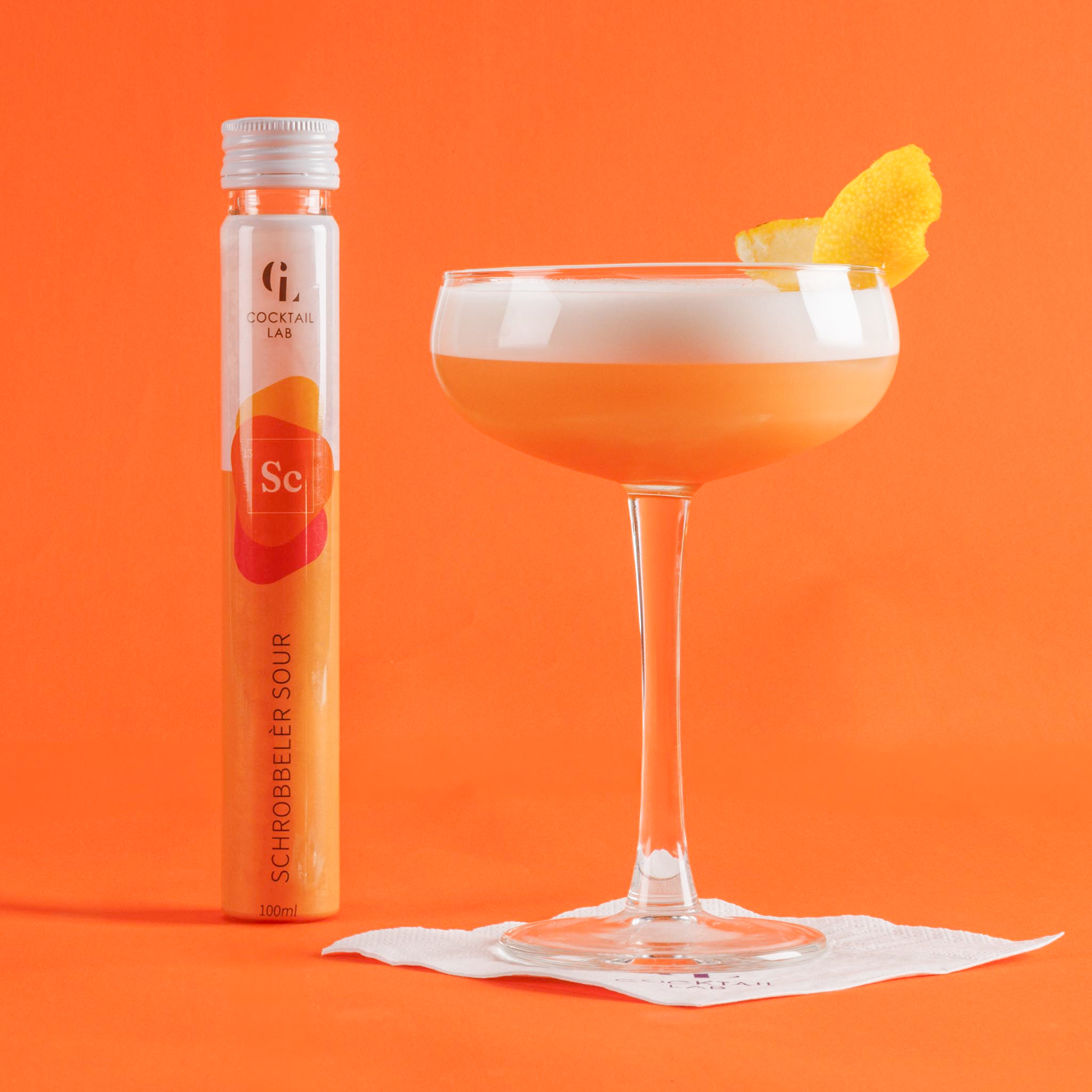 Schrobbeler Sour tube and served cocktail in coupe glass with foam and orange peel - Cocktail Lab
